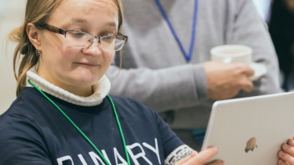 Woman holding an ipad wearing a tshirt with the words Binary Shift