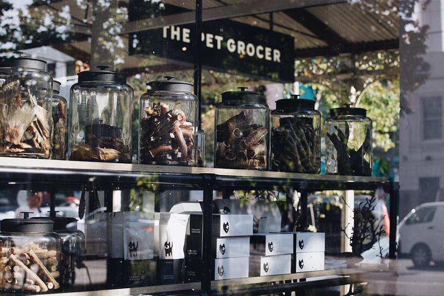 The  front window of the Pet Grocer store front with jars and boxes of pet treats